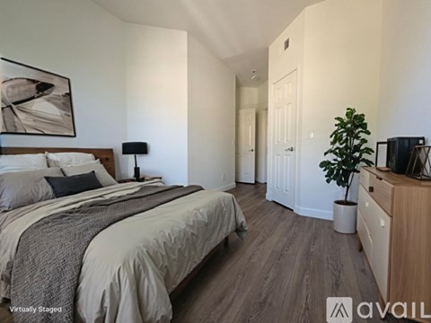 A bedroom with a large bed and a plant on the side table.