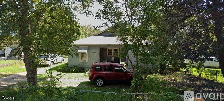 A red car is parked in front of a house.