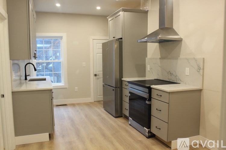 A kitchen with a refrigerator, oven, and sink.
