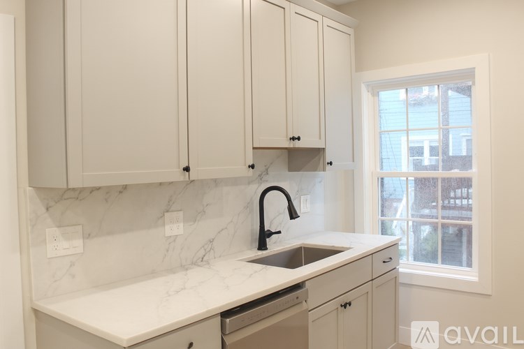 A kitchen with white cabinets and marble countertops.