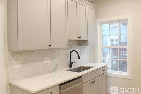 A kitchen with white cabinets and marble countertops.
