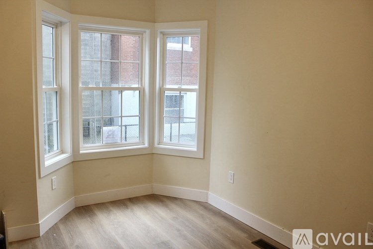A room with a window and a wooden floor.