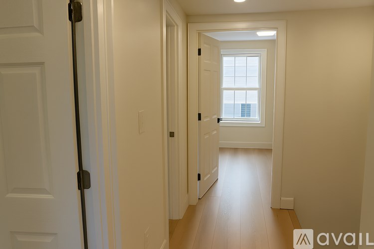 A hallway with a door on the left and a window on the right.