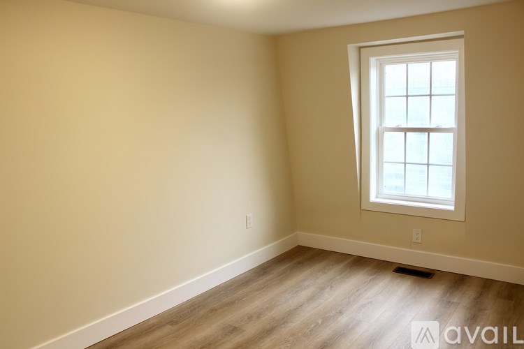 A room with a window and wooden flooring.
