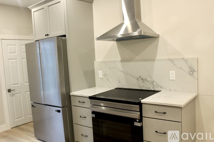 A kitchen with a stainless steel refrigerator, a stove with an oven, and a marble countertop.