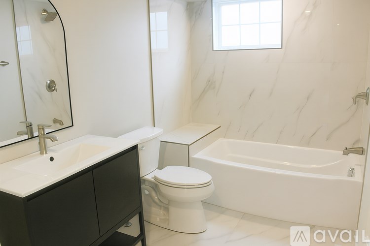 A bathroom with a marble wall and a white bathtub.