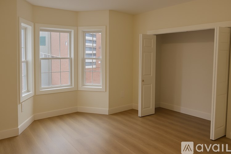 A room with wooden floors and three windows.
