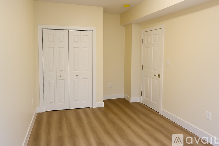 A room with two white doors and wooden flooring.