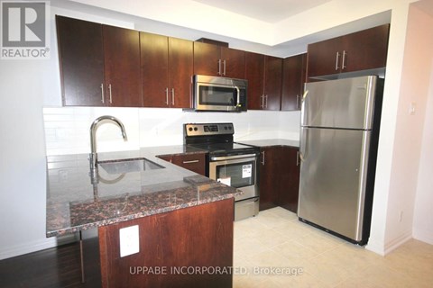 A kitchen with a refrigerator, microwave, oven, and sink.