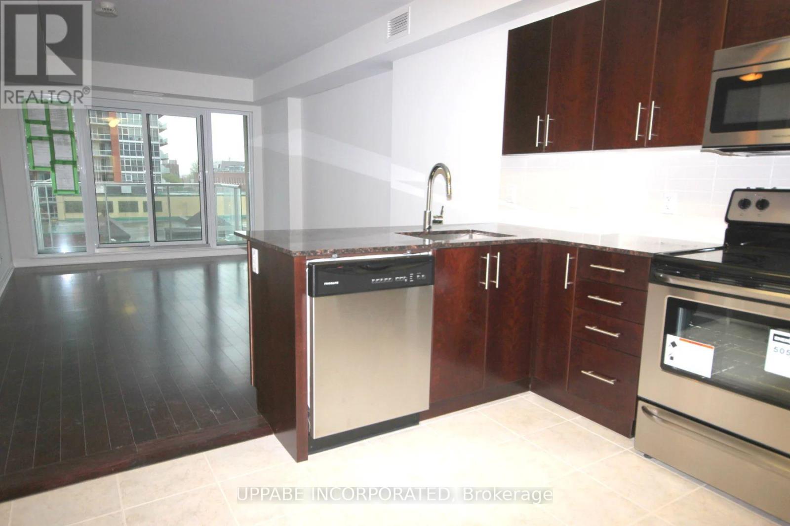 A kitchen with dark wood floors and white walls.