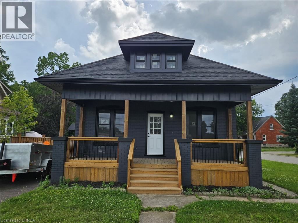 A small house with a black roof and wooden porch.