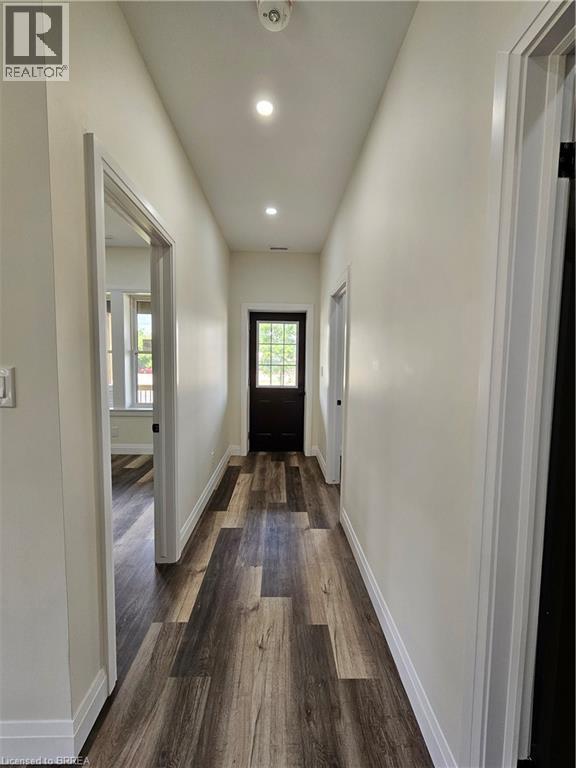A hallway with wood flooring and white walls.