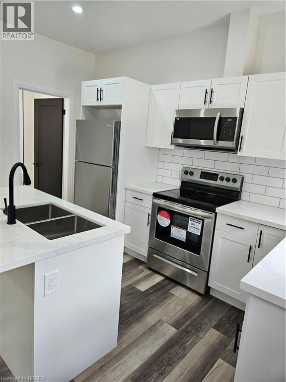 A kitchen with white cabinets and a stainless steel refrigerator.