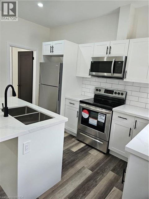 A kitchen with white cabinets and a stainless steel refrigerator.