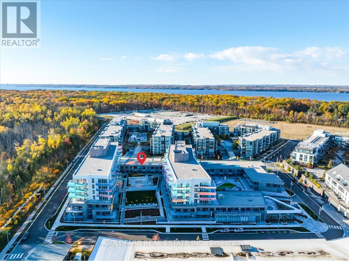 An aerial view of a real estate complex with a road and a body of water in the background.