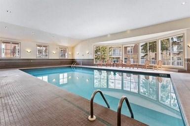 A large indoor swimming pool with a glass barrier and a tiled floor.