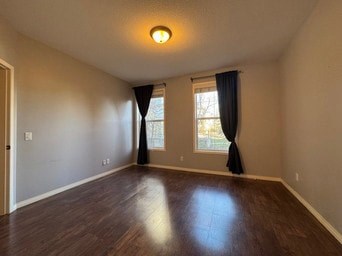A room with wooden floors and a window with black curtains.