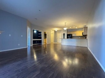 A spacious room with a dark wood floor and white walls.