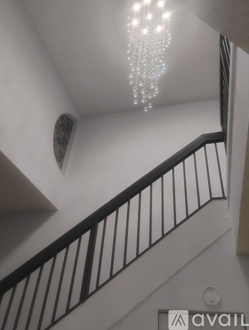 A chandelier hangs from the ceiling of a stairwell.