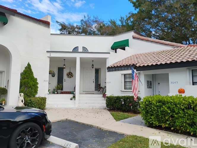 A white house with a black car parked in front.