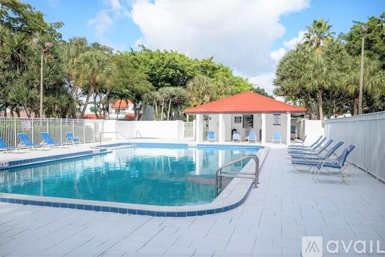 A pool with a red roof and blue loungers.