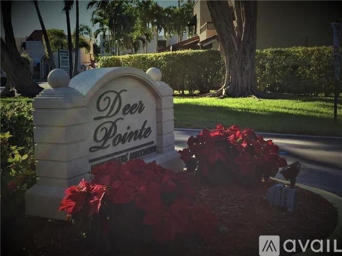 A sign that says "Deer Park" is surrounded by red flowers.