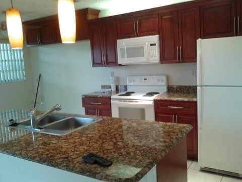 A kitchen with granite countertops and white appliances.
