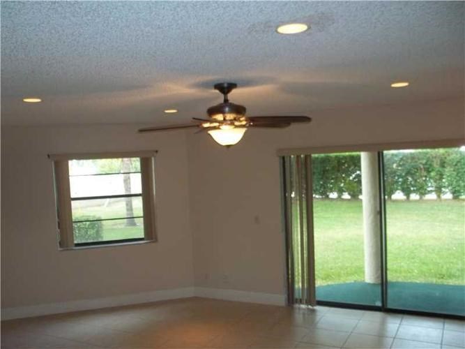 A room with a ceiling fan and sliding glass doors.