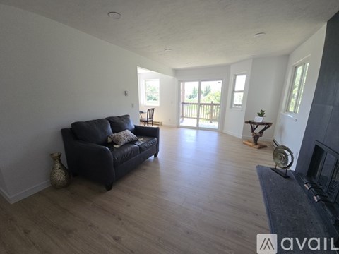 A living room with a black couch and wooden floors.