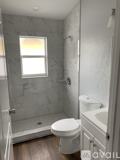 A bathroom with a toilet, sink, and a window.
