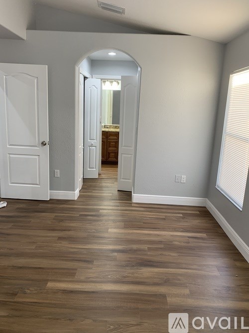A hallway with wood flooring and white walls.