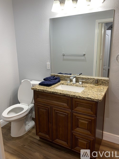 A bathroom with a toilet, sink and mirror.