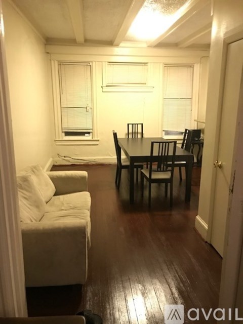 A living room with a couch, chairs, and a dining table.