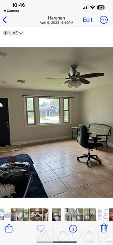 A room with a ceiling fan and a window overlooking a house.