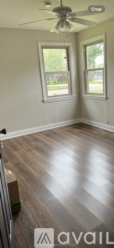A room with a ceiling fan and two windows.