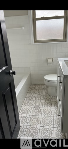A bathroom with a toilet, a tub, and a window.