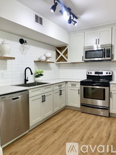 A kitchen with wooden floors and white cabinets.