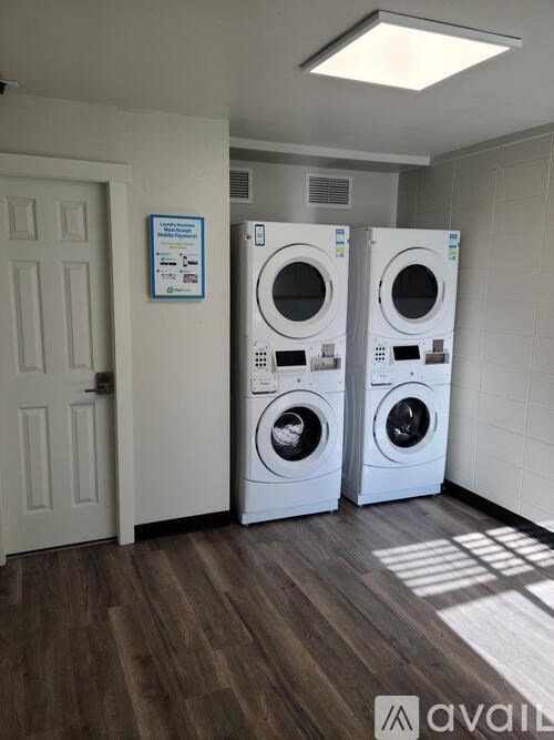 Two washing machines in a laundry room with a sign on the wall.