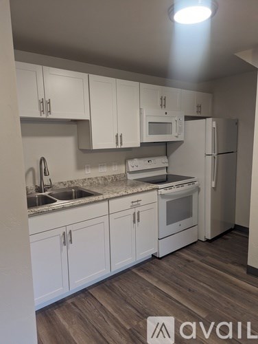 A kitchen with white cabinets and a wooden floor.