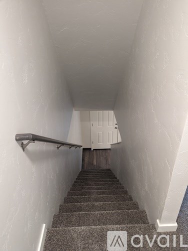 A stairway with a metal handrail leading to a door at the top.