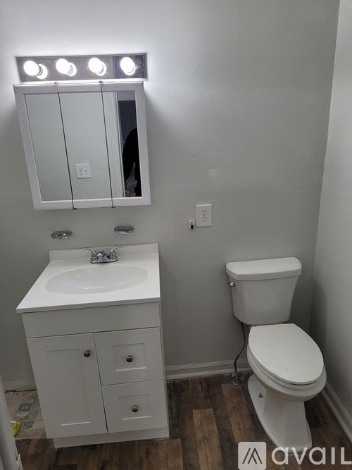 A white bathroom with a toilet, sink, and mirror.