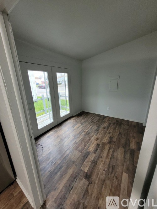 A room with wooden flooring and white walls.