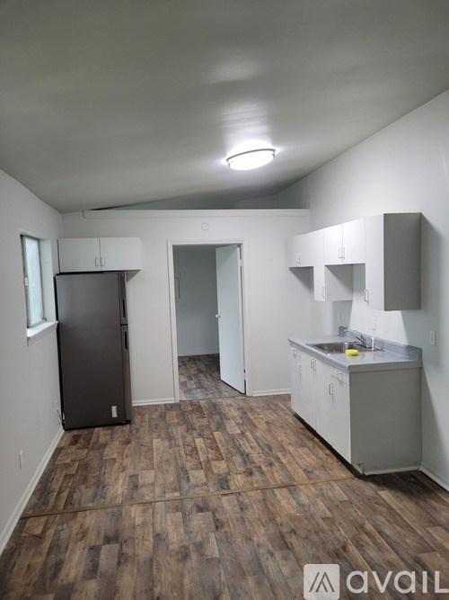 A kitchen area with a refrigerator, sink, and cabinets.