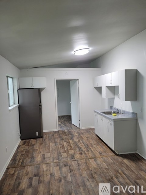 A kitchen area with a refrigerator, sink, and cabinets.