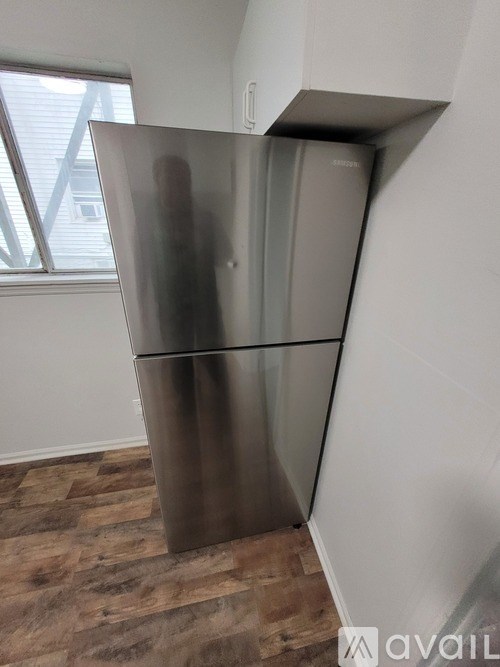 A stainless steel refrigerator in a room with wooden flooring.