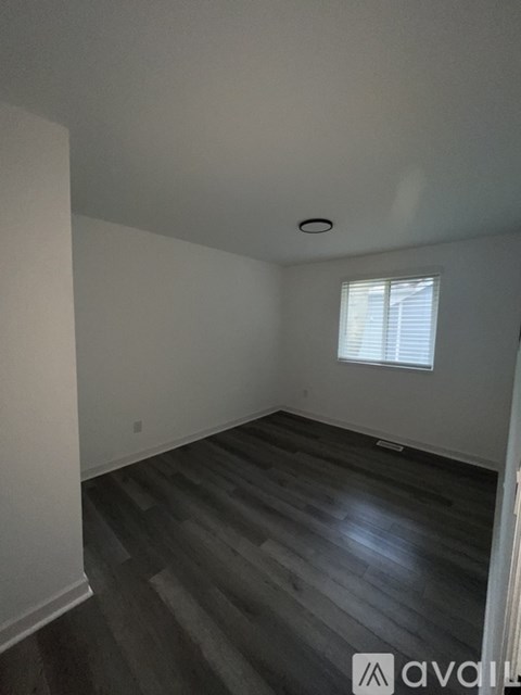 A room with wooden flooring and a window with blinds.