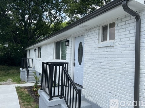 A white house with a black railing and a white door.