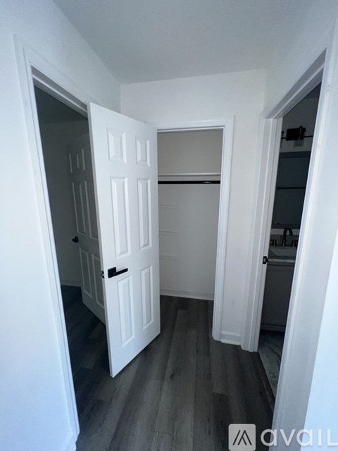 A white door is open to a room with a wooden floor.