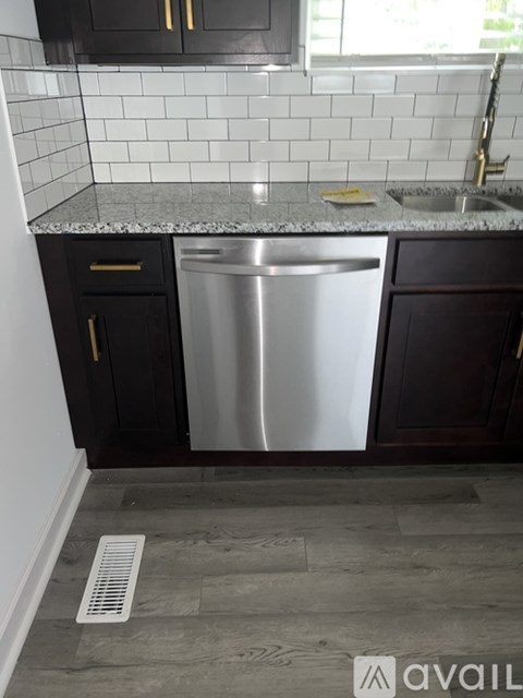 A kitchen with a stainless steel dishwasher and black cabinets.