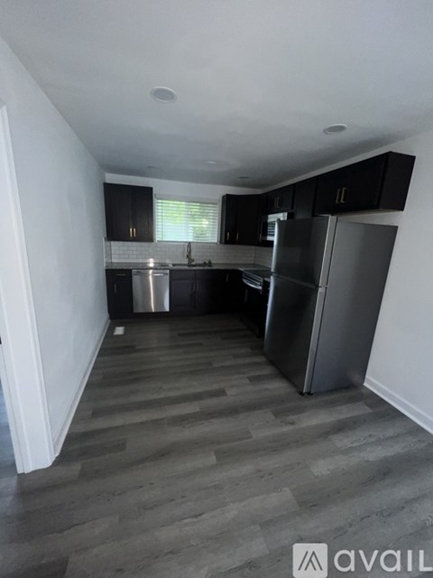 A kitchen with a refrigerator, sink, and cabinets.